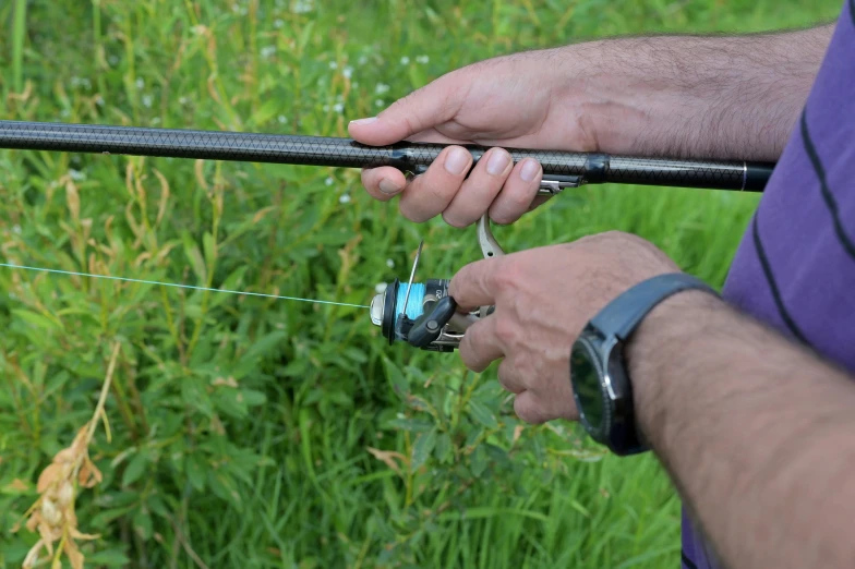 a man is standing in a field while holding two fishing rods