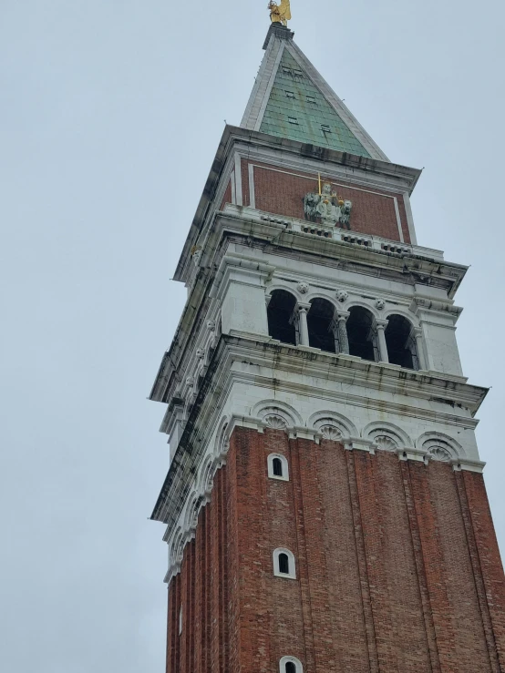 a large clock tower with a gold statue atop it