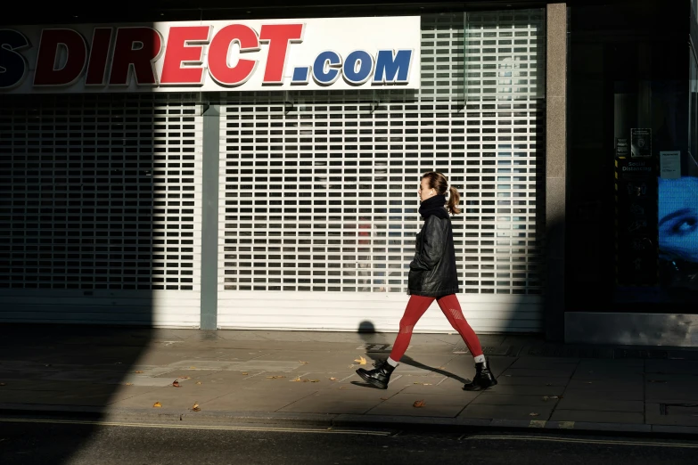 a woman walking on a sidewalk in front of a store