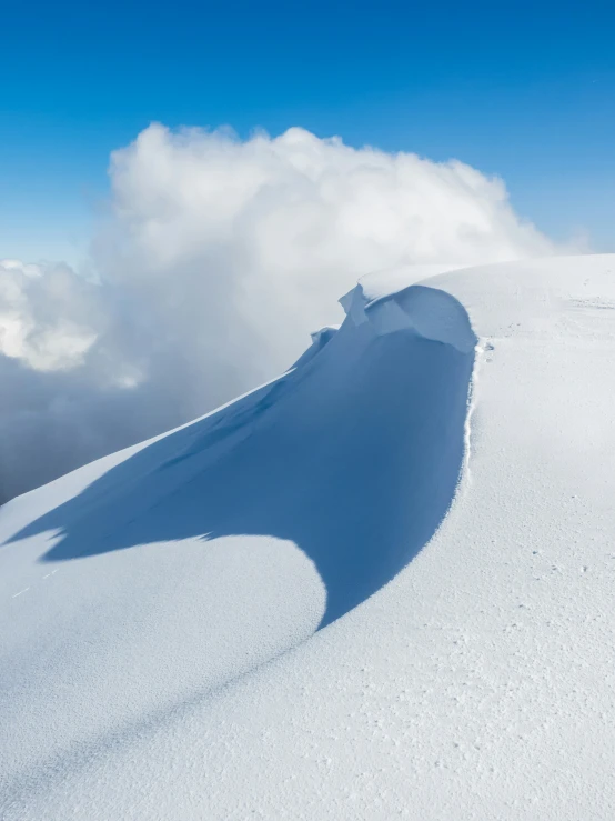 a large snowy mountain that is in the middle of some clouds