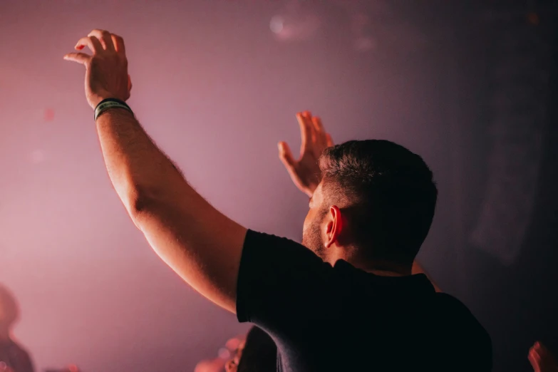 a man in black shirt performing on stage with arms up