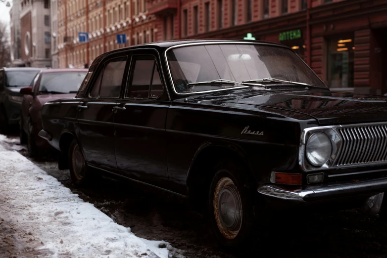 a vintage car is parked on the side of a snowy street