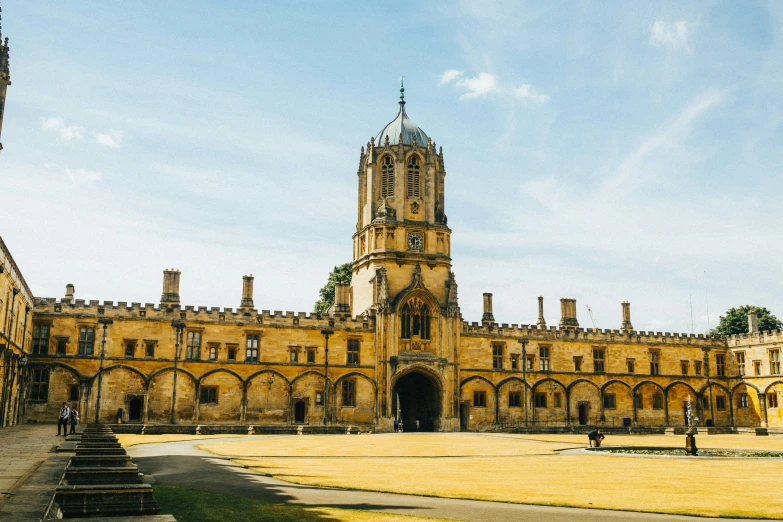 a stone building with a tall tower and some people standing outside of it