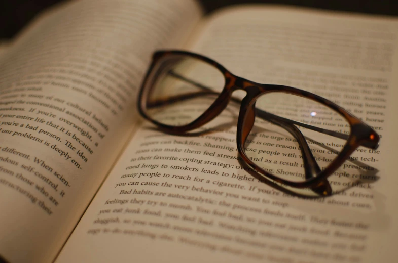 the book is opened to show glasses on it