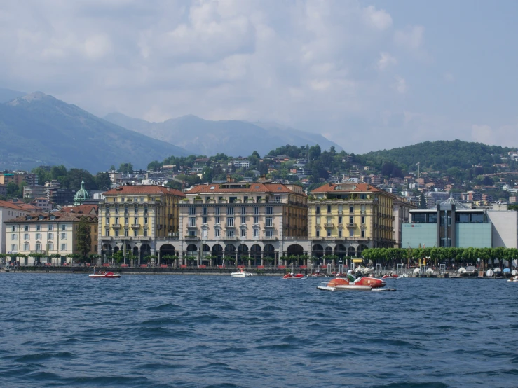 the buildings are located along the water in front of mountains