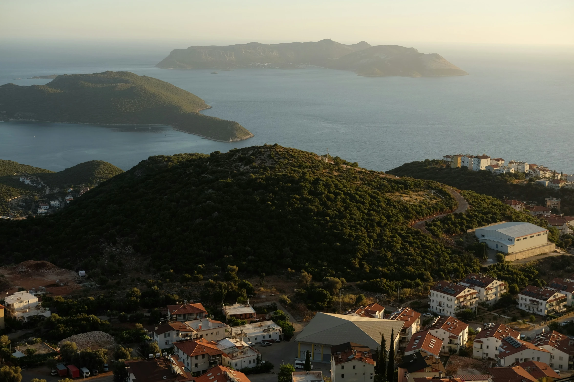 an island in the ocean with buildings and green hills