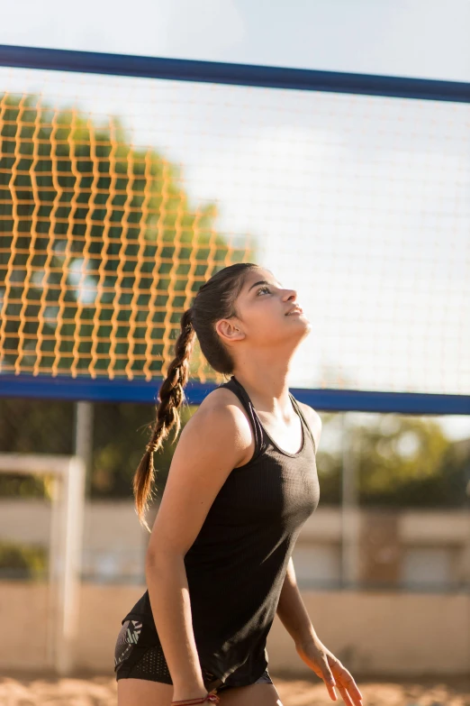 a girl in black playing volleyball and about to strike a ball