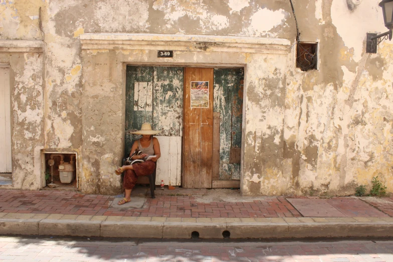 an older man sitting in front of his home