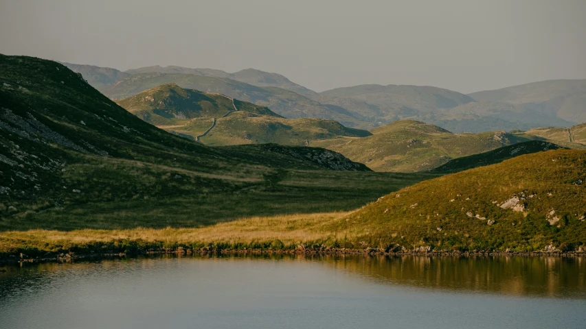 the mountains are shown by the water and in the distance is grass and water