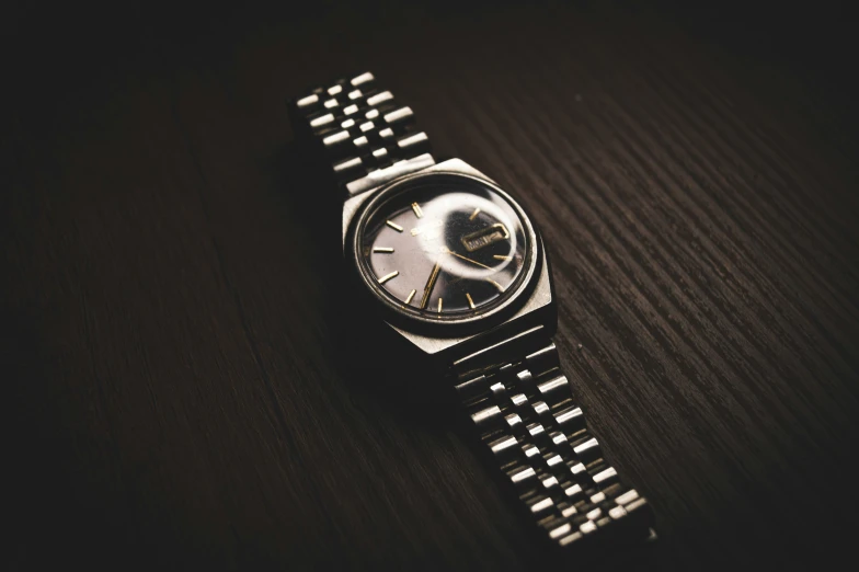 a watch on a table with dark wood material