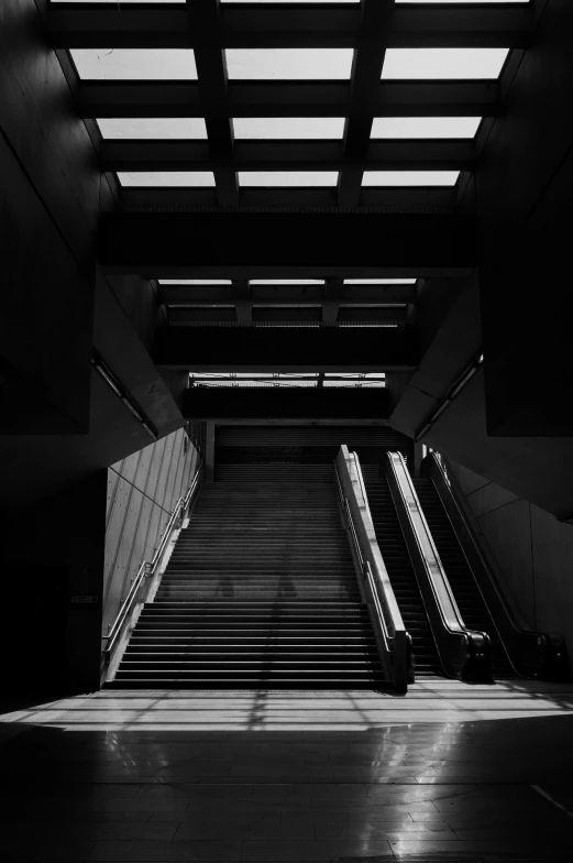 an escalator in a large building has its light streaming through the ceiling