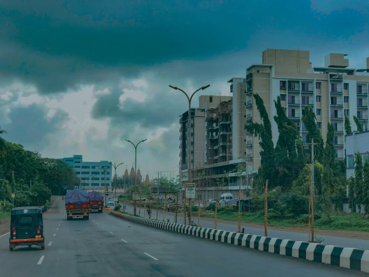 three trucks driving on the road under cloudy skies