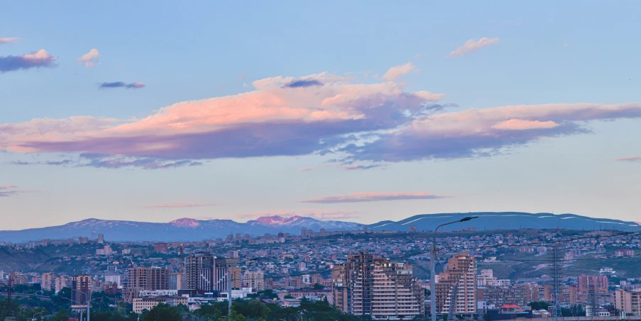 the city and mountains at dusk with a cloud filled sky