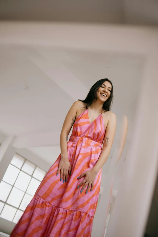 an attractive woman standing by a wall smiling