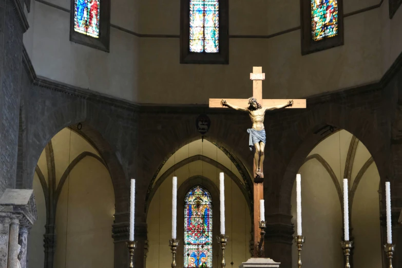 a large cross in an old church with a stained glass window