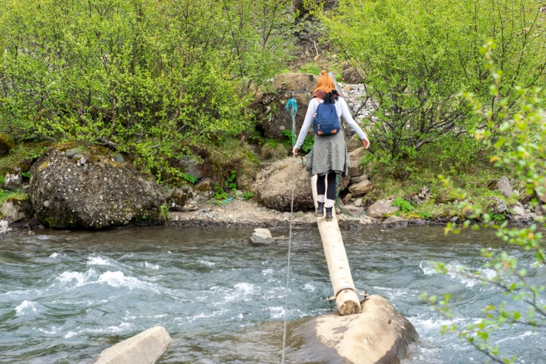 a woman crossing a river on a tight rope