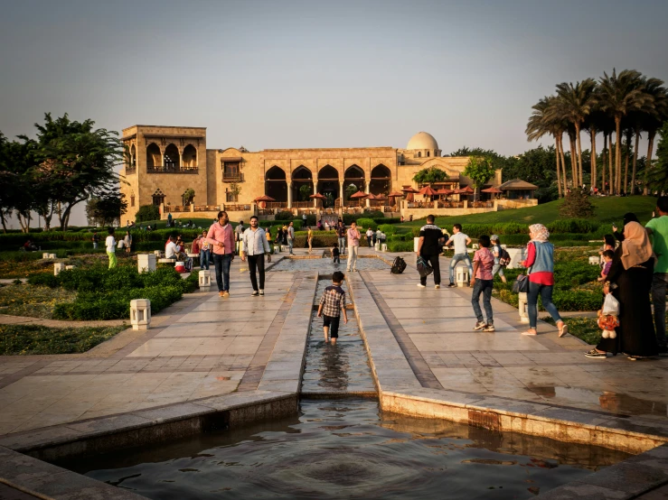 tourists walking through a large courtyard lined with palm trees