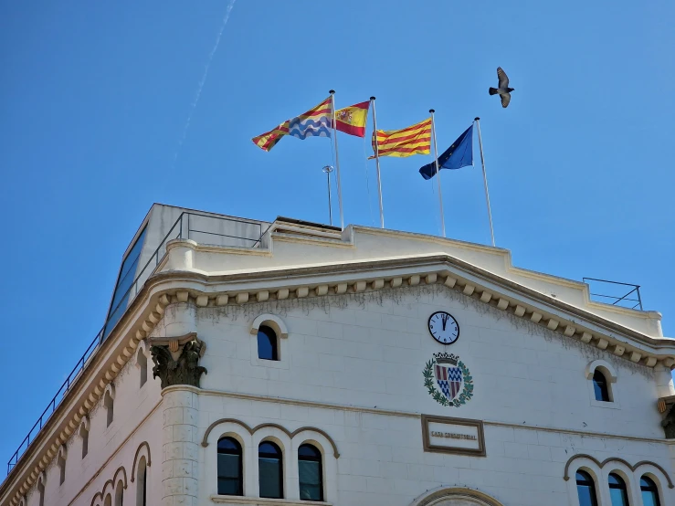 flags and clock tower on roof of city building