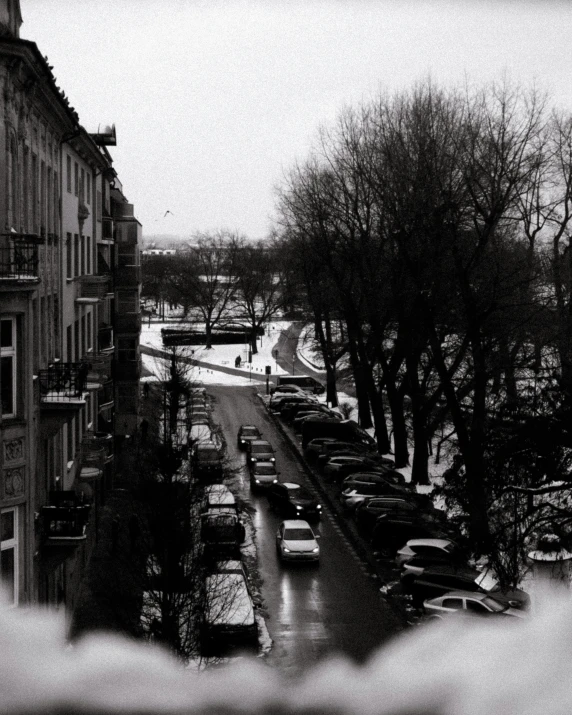 a city street with snow falling and cars parked