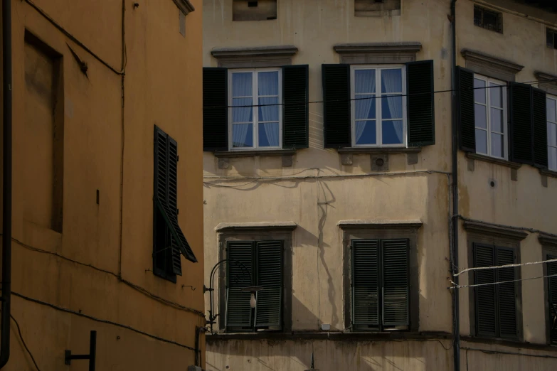 two tall buildings with windows and some black shutters