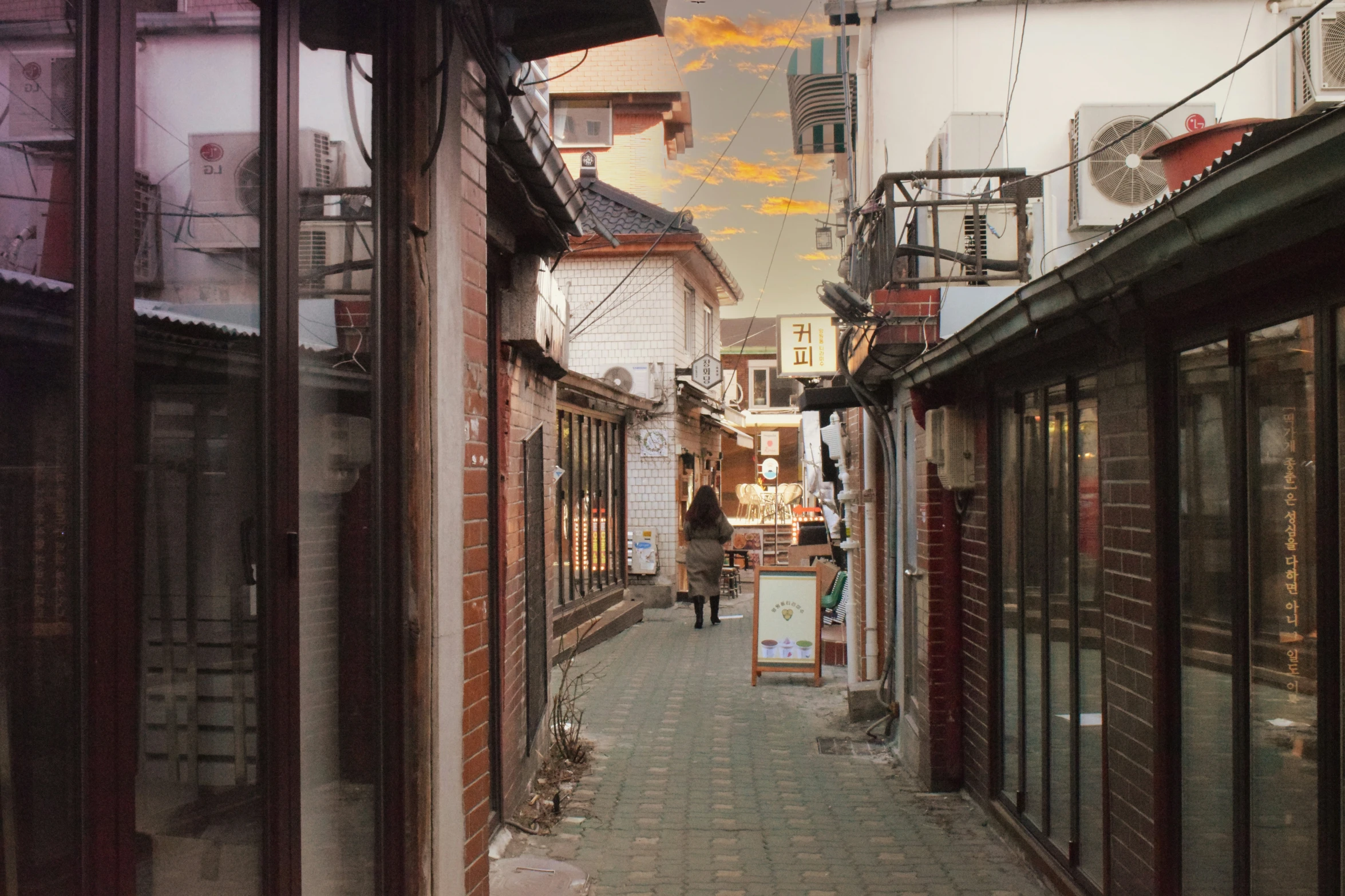 a woman walks down a brick alley lined with stores