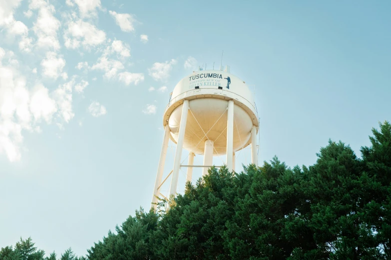 a water tower with a light orange top and blue sky