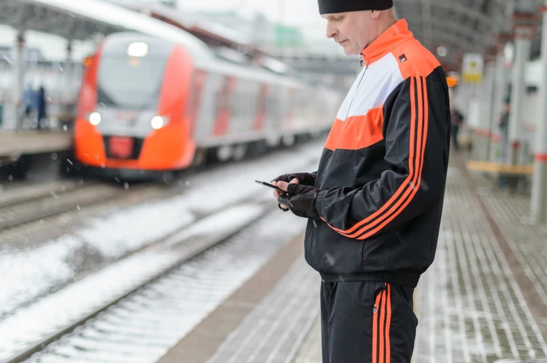 a man stands in front of a train as it drives down the track