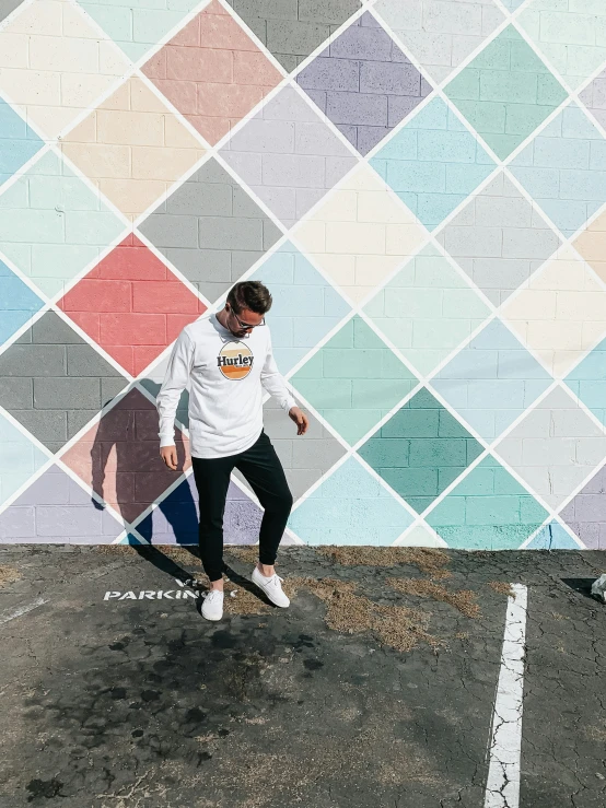 the young man is wearing sneakers near a colorful wall