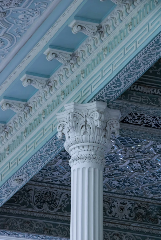 a white column with blue and white details beneath the roof