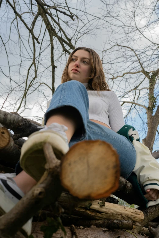 a woman sitting on top of a tree with no leaves