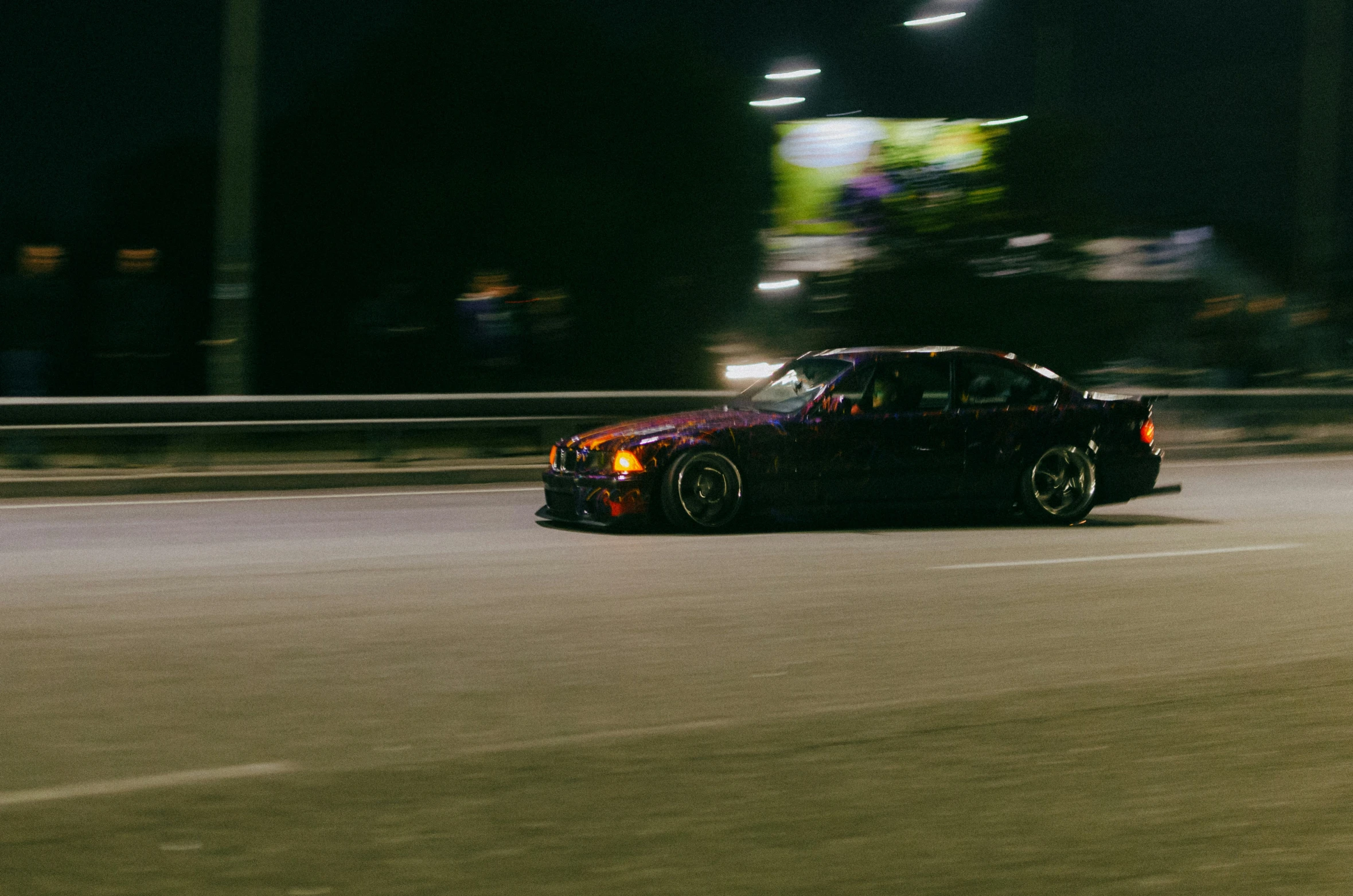 a car driving on a track at night with lights in the background