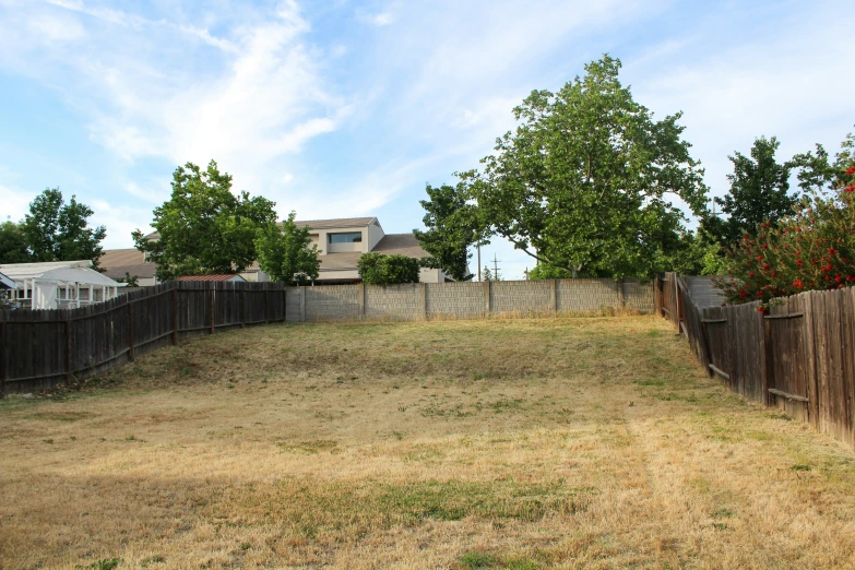 a fenced in backyard next to a building with trees