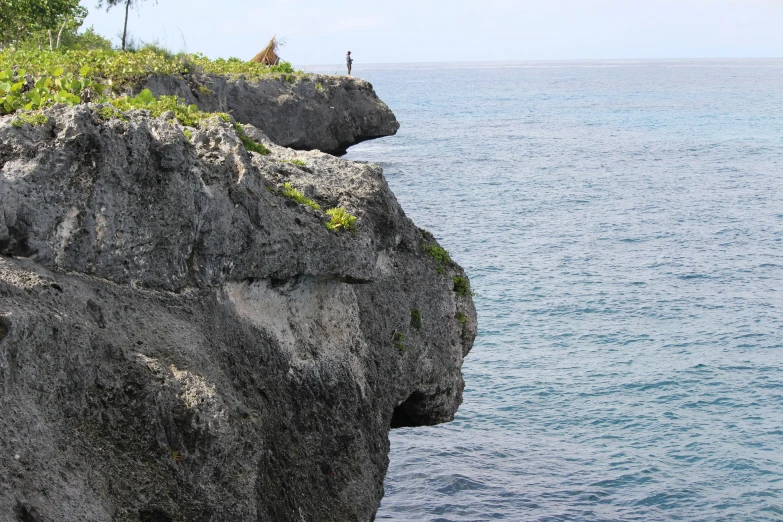 a person sitting on top of a large rock cliff