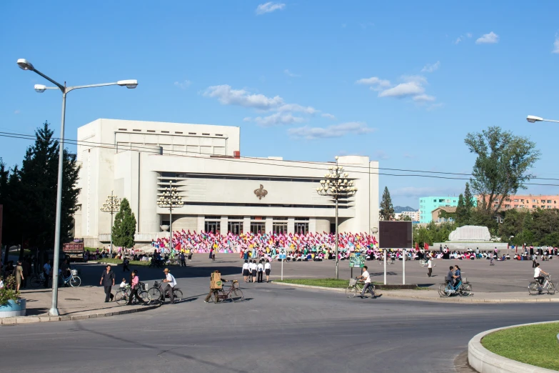 people riding bicycles in front of a building that is very large