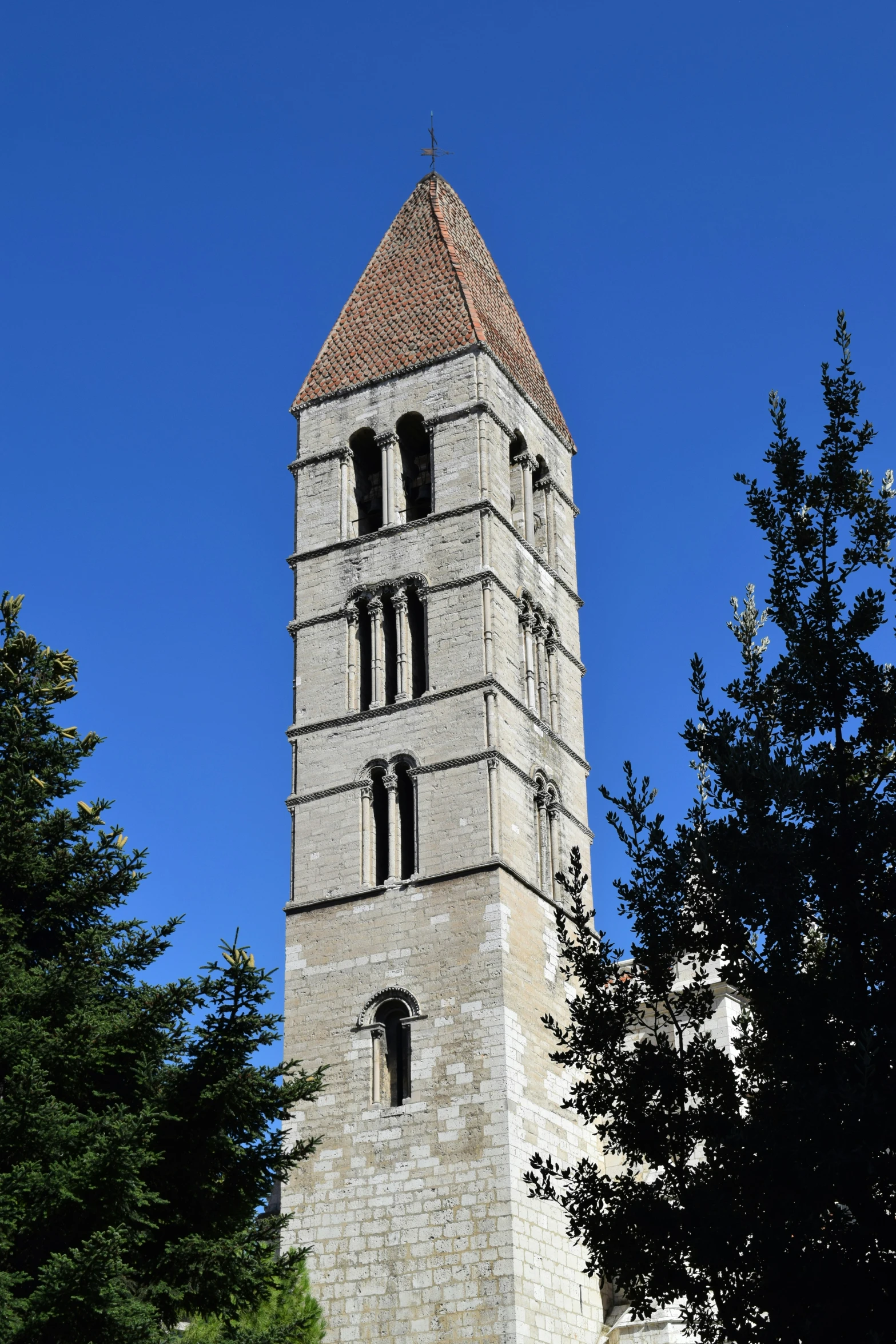 the large gray clock tower is next to a group of trees