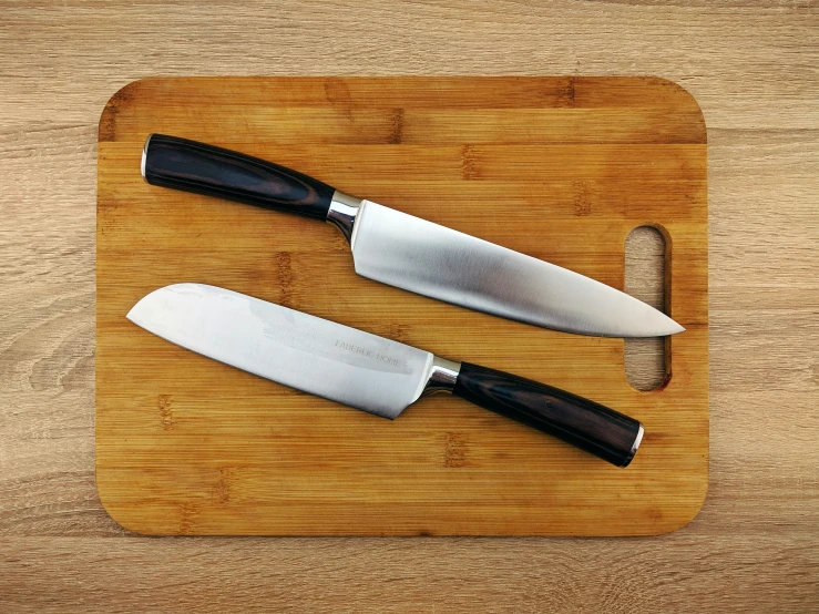 two knives are on top of a wooden board