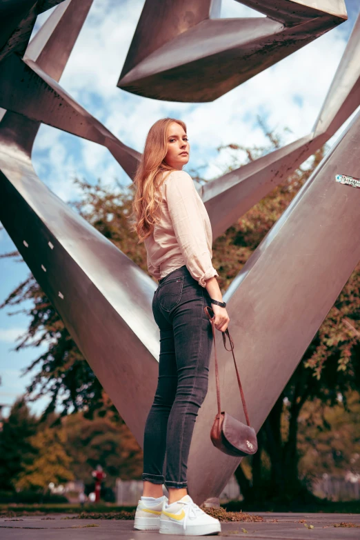 a beautiful young woman standing next to an abstract sculpture