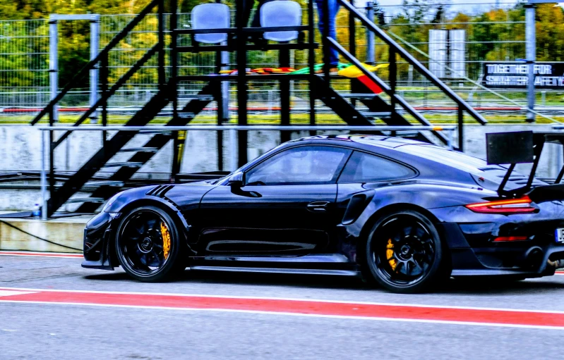 black car with yellow rims driving through the track