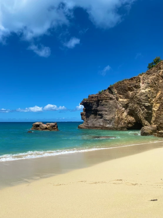 an empty beach with a rock outcropping in the distance