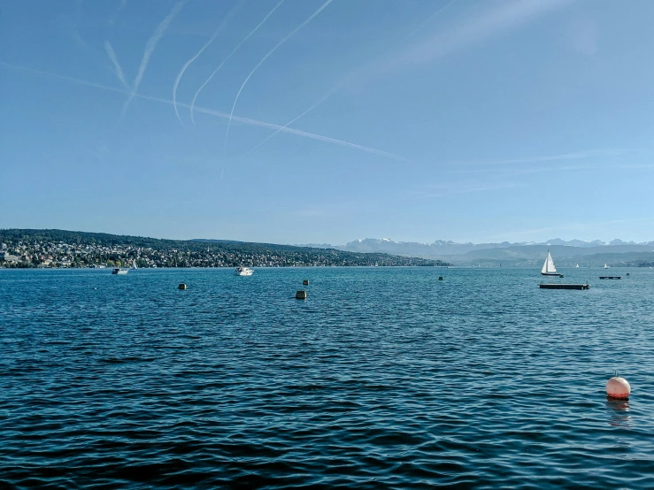 there are sailboats sailing in the water by a mountain