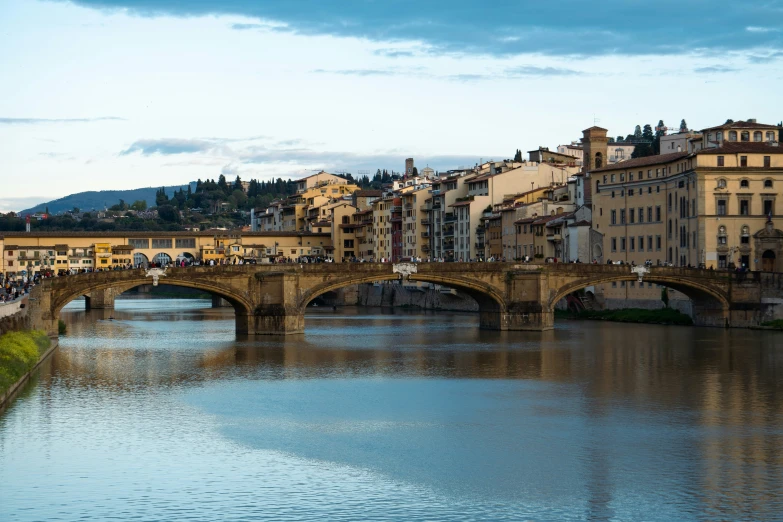 a river runs underneath an old bridge that has many old buildings lining it