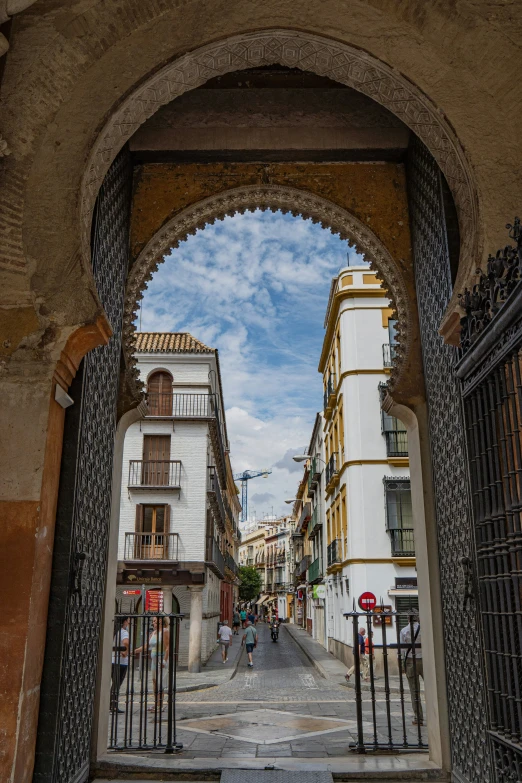 an arch is opening to reveal the courtyard of some houses