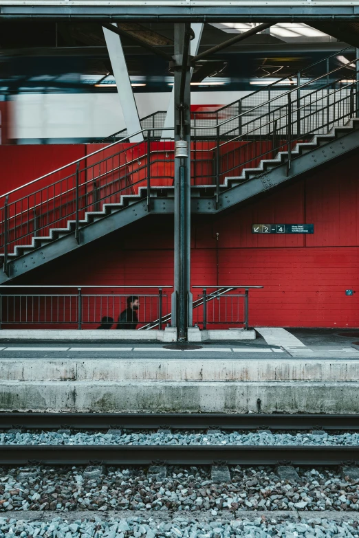 two men are sitting on the bench under a railing, and there is a train passing by