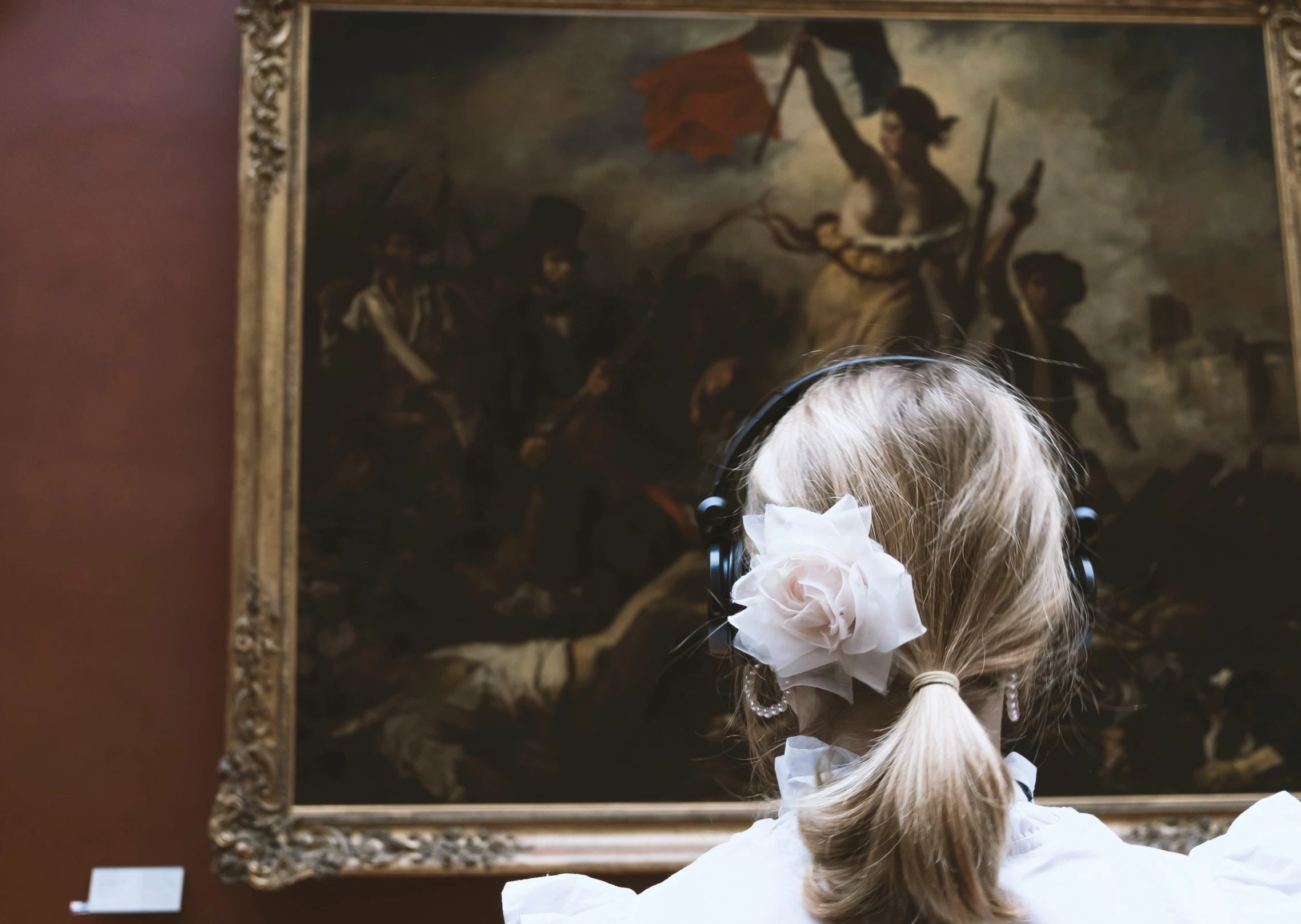 a girl in headphones standing next to a painting