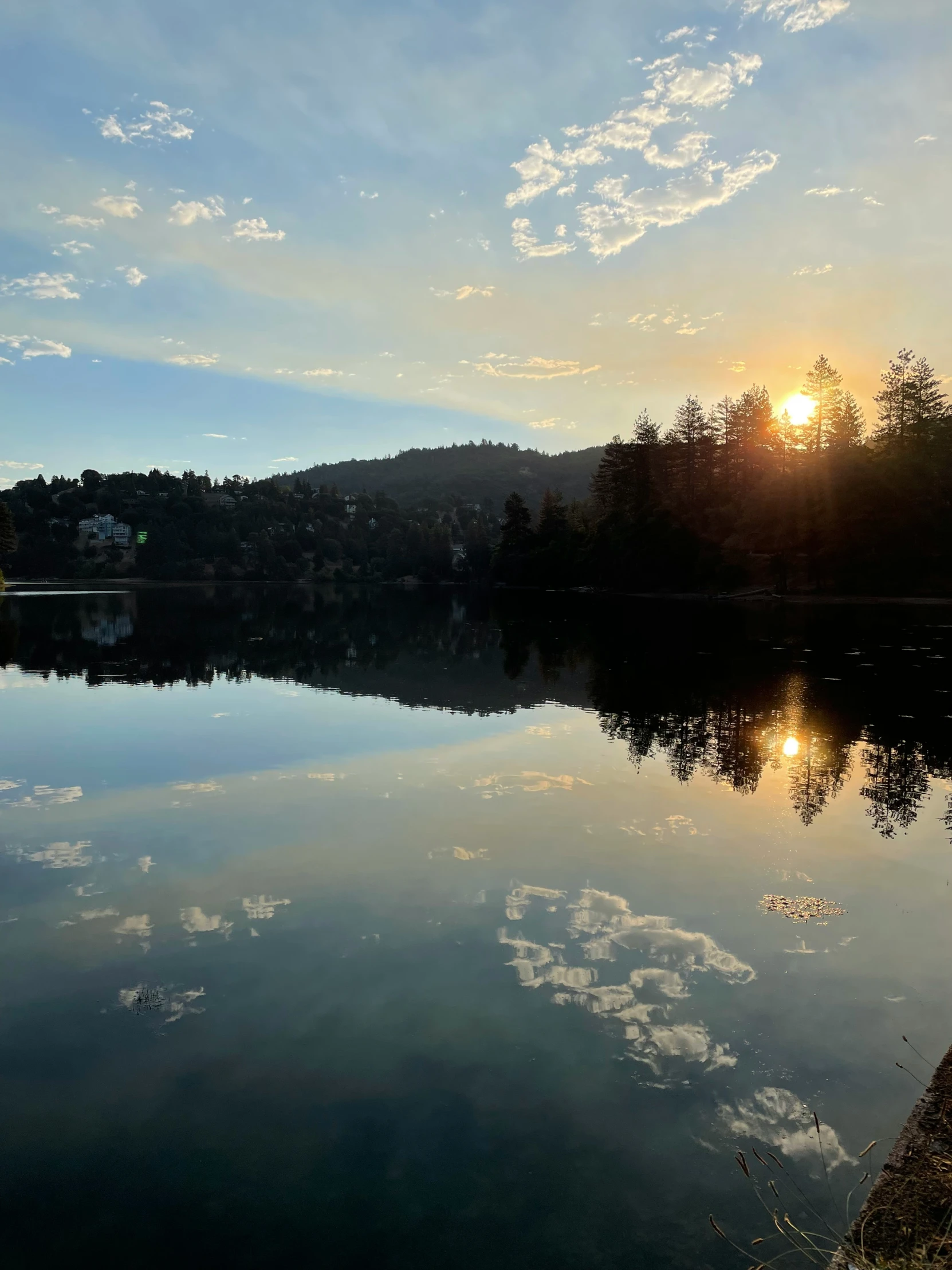 the sun rises above the clouds and the sky is reflected in a lake