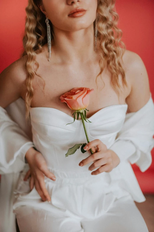 the woman is holding a rose by her arm