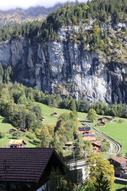 an aerial view of green pastures near mountains and rocks