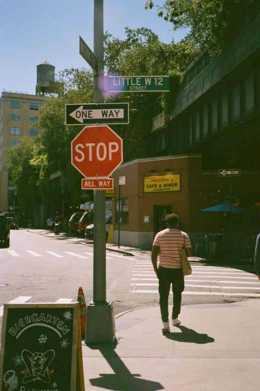 a man walks down the sidewalk toward a street stop sign