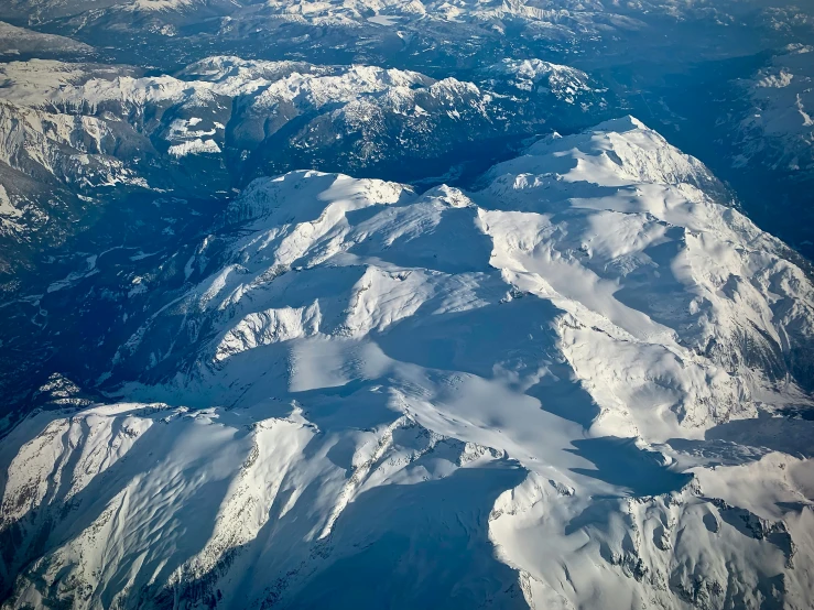 some snowy mountains and snow capped hills seen from above