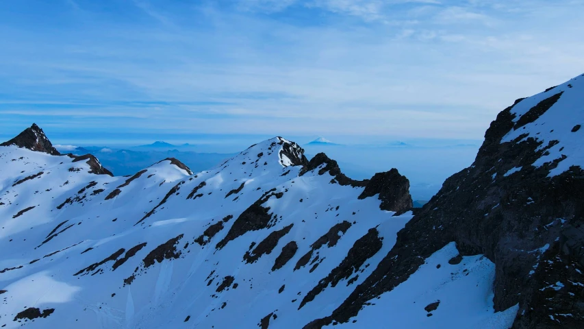 some tall mountains in the snow and blue sky